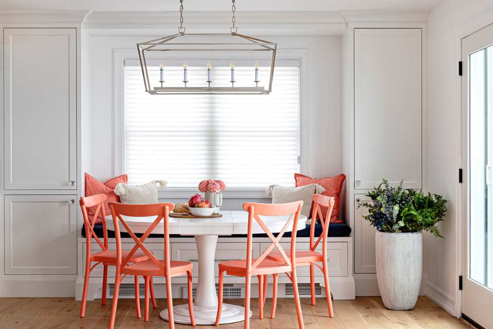 breakfast nook in designer home with bold peach throw pillows and accent chairs